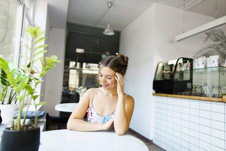 Young lovely girl sitting at cafe and waiting boyfriend. Concept of dating and beautiful female person.の写真素材