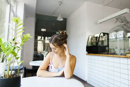 Young pretty girl sitting at cafe and waiting boyfriend. Concept of dating at restaurant and beautiful female person.の写真素材