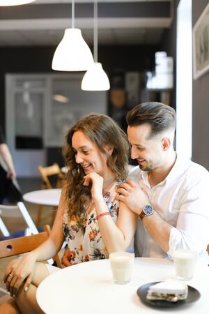 Young handsome man hugging woman at cafe, ,sitting near cups of coffee. Concept of positive emotions, feelings and resting on lunch.の写真素材