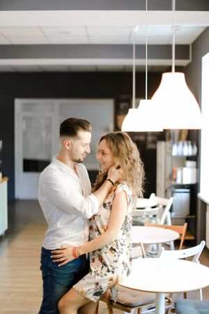 Young european man hugging woman and standing at cafe near table. Concept of togetherness and positive feelings, love and happiness.の写真素材
