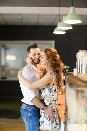 Young cute wife hugging husband at cafe near bar. Concept of happy couple and contemporary interior.の写真素材