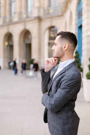 Young american boy wearing grey suit standing near building. Concept of male fashion and successful businessman.の写真素材