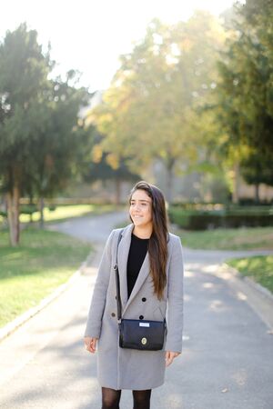 Caucasian pretty girl wearing coat standing outside and walking. Concept of strolling female person.の写真素材