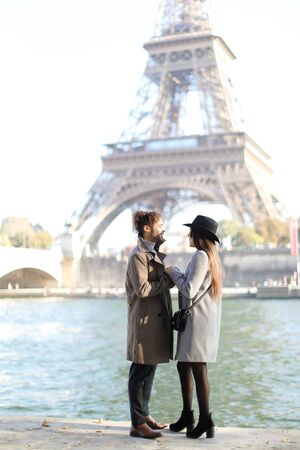 Back view of afro american man and girl hugging and standing near Eiffel Tower in Paris. Concept of France landmark and love, happy couple.の写真素材