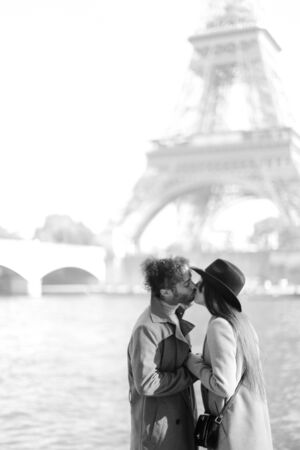Afro american man kissing woman in hat near Eiffel Tower, Paris. Concept of love and France tour.の写真素材