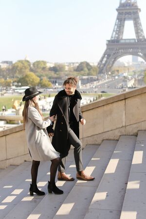 Afro american handsome boy and caucasian girl walking on stairs, Eiffel Tower in background, Paris.Concept of love and international couple, vacations in France.の写真素材