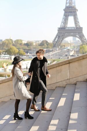 Afro american boy and caucasian woman walking on stairs, Eiffel Tower in background, Paris.Concept of love and international couple, vacations in France.の写真素材