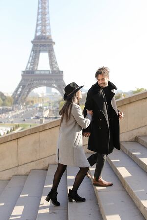 Afro american young boy and caucasian girl walking on stairs, Eiffel Tower in background, Paris.Concept of love and international couple, vacations in France.の写真素材