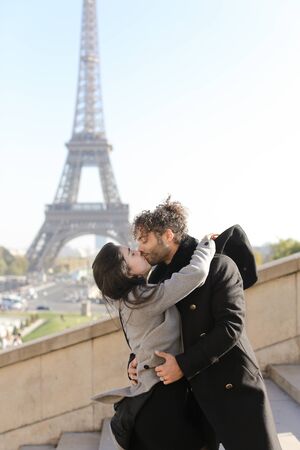 Afro american handsome boy and caucasian girl hugging on stairs, Eiffel Tower in background, Paris.Concept of love and international couple, vacations in France.の写真素材