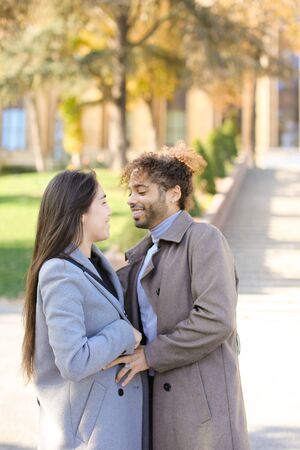 Afro american handsome man hugging caucasian girlfriend outside. Concept of international couple and love.の写真素材