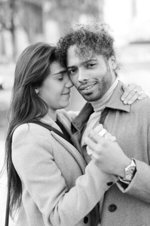 Black and white photo of afro american man hugging caucasian pretty girlfriend outside. Concept of international couple and love.の写真素材
