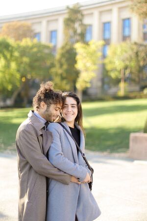 Afro american handsome man hugging caucasian pretty girlfriend outside. Concept of international couple and love.の写真素材