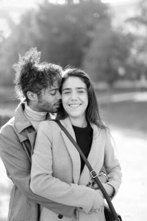 Black and white photo of afro american man hugging caucasian nice girlfriend outside. Concept of international couple and love.の写真素材