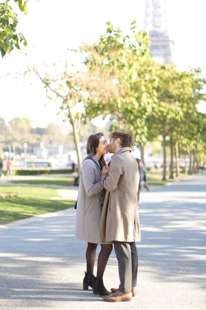 Afro american man kissing caucasian girlfriend and walking in park.の写真素材