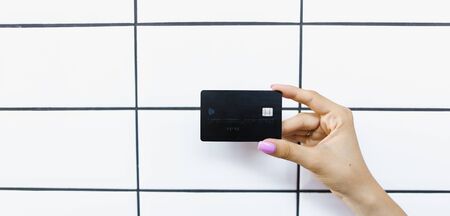 Banner of caucasian hands holding debit card in white tile wall background. Concept of bank account and credit.の写真素材