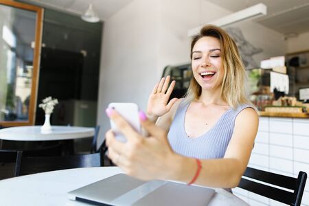 Young girl talking with video call by smartphone near closed laptop. Concept of modern technology and conversation.の写真素材
