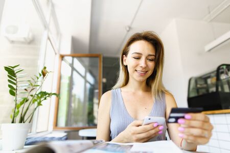 Focus on girl using smartphone and credit card for shopping online. Concept of booking tickets and tours.の写真素材