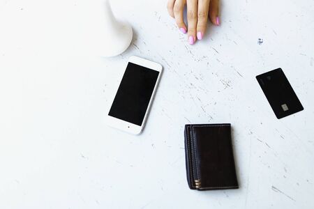 White smartphone, leather wallet and credit card lying near female hand. Concept o modern technology and paying online.の写真素材