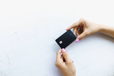 Hand with pink manicure keeping black debit card in white background. Concept of bank account and credit.の写真素材