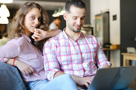 Young european woman and man using laptop at cafe and surfing. Concept of free hotspot and fast internet, modern technology and happy couple.の写真素材