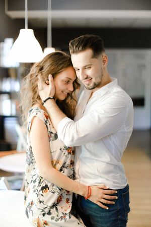 Young caucasian boy wearing white shirt and hugging cute girl inside. Concept of love and togetherness, happy couple.の写真素材