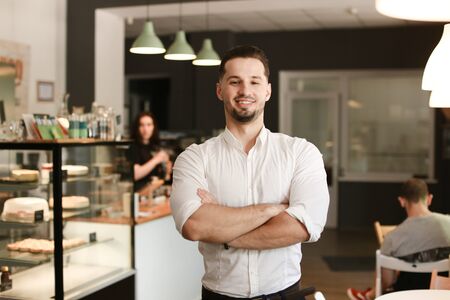 Young male smiling businessman standing with at cafe. Concept of business and success.の写真素材