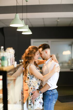 Young caucasian wife hugging husband at cafe near bar. Concept of happy couple and contemporary interior.の写真素材