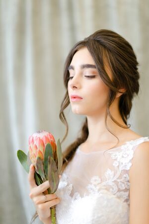 Portrait of pretty beautiful brunette caucasian bride with flowers at studio. Concept of bridal photo session and bridal makeup.の写真素材