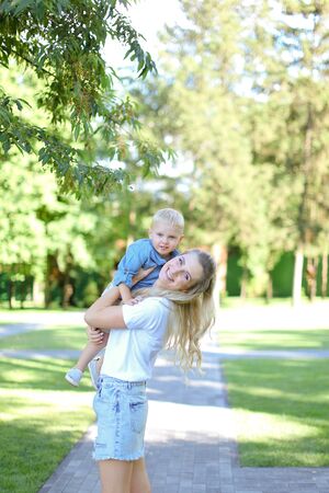 Young blonde mother playing with little son outside. Concept of motherhood and kids.の写真素材