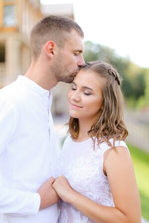 European groom kissing bride and holding hands outdoors. Concept of wedding and bridal photo session, relationship.の写真素材