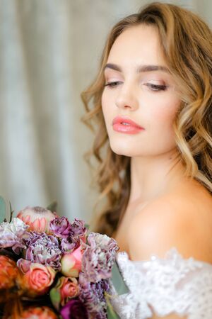 Close up portrait of gorgeous bride with bouquet of flowers at studio. Concept of floristic art, beauty and beautiful wedding photo session.の写真素材