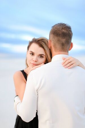 Young girl hugging man in white field background. Concept of love and winter photo session.の写真素材