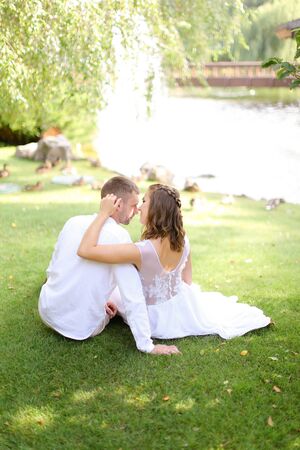 Young couple sittling near lake on grass. Concept of relationships, youth and love.の写真素材