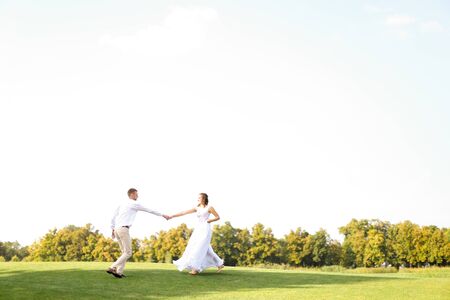 Groom and bride dancing and playing on grass. Concept of wedding photo session on open air and nature.の写真素材