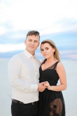 Young happy woman wearing transparent black dress hugging man in snowed steppe. Concept of winter photo session and love.の写真素材