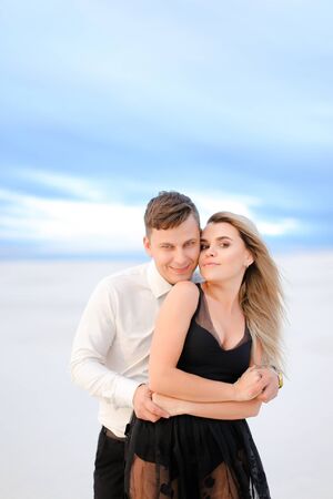 Young man hugging woman in white snowing background in steppe. Concept of winter photi session and romantic love.の写真素材