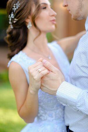 Close up fiancee dancing with groom outside, focus on hand rings. Concept of wedding and bridal photo session.の写真素材