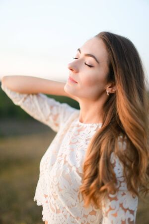 Portrait of caucasian pretty fiancee standing in steppe and wearing white dress. Concept of nature, bridal photo session on nature and beauty.の写真素材