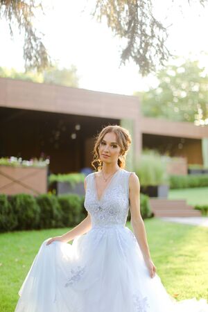 Caucasian beautiful fiancee walking in park, sun rays. on green grass. Concept of bridal photo session andの写真素材