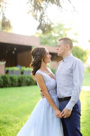 Caucasian fiancee dancing with groom in park and wearng white dress. Concept of married couple and bridal photo session in open air.の写真素材