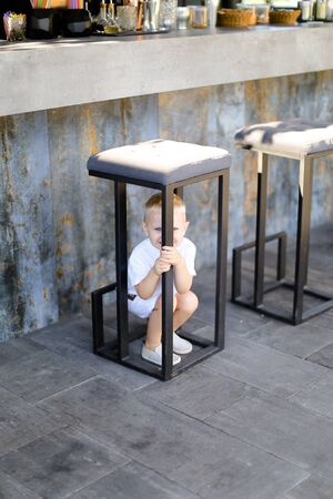 Little male baby wearing white clothes and playing outside at street cafe. Concept of childhood.の写真素材