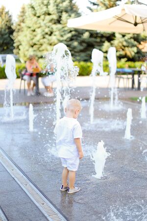 Little male baby standing near fountain. Concept of walking in city with children.の写真素材