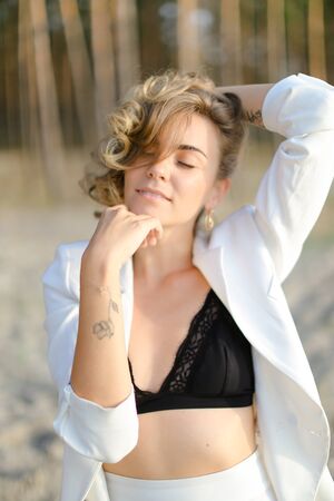 Portraint of young fashionable girl with little hand tattoo wearing white shirt and black bra. Concept of beauty.の写真素材