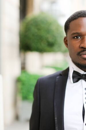Portrait of afro american happy man wearing dark suit and standing outdoors. Concept of black businessman.の写真素材