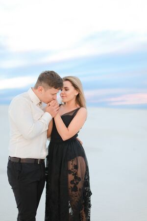 Young pretty woman wearing transparent black dress hugging man in snowed steppe. Concept of winter photo session and love.の写真素材
