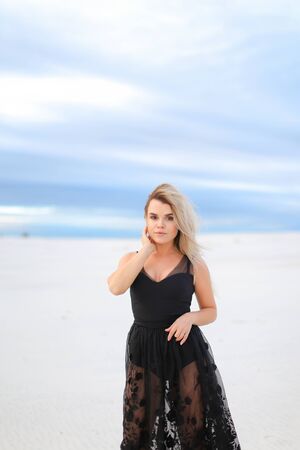 Young beautiful woman wearing black transparent dress and walking on snow. Concept of vogu and seasonal photo session.の写真素材