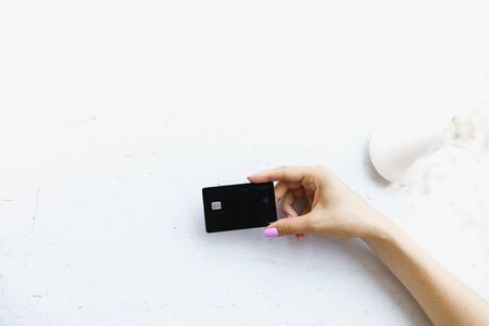 Hand keeping black debit card in white background. Concept of bank account and credit.の写真素材