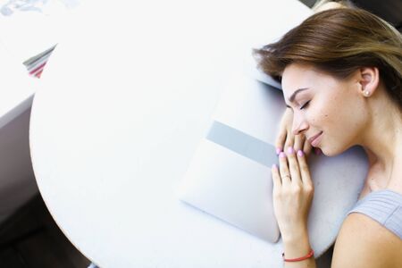 Blonde studdent lying on laptop at cafe in white background with copy space. Concept of having break...