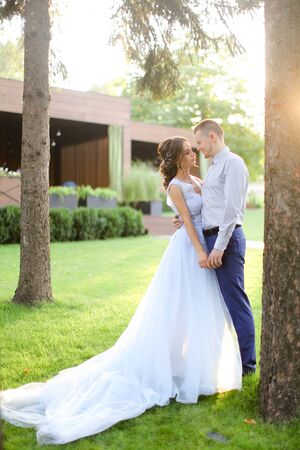 Caucasian young fiancee dancing with groom in park and wearng white dress. Concept of married couple and bridal photo session in open air.の写真素材