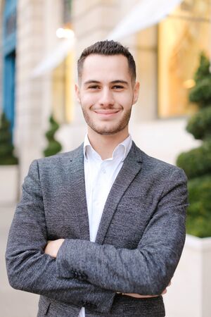 Portrait of young caucasian boy wearing grey suit outside. Concept of successful businessman and male fashion.の写真素材